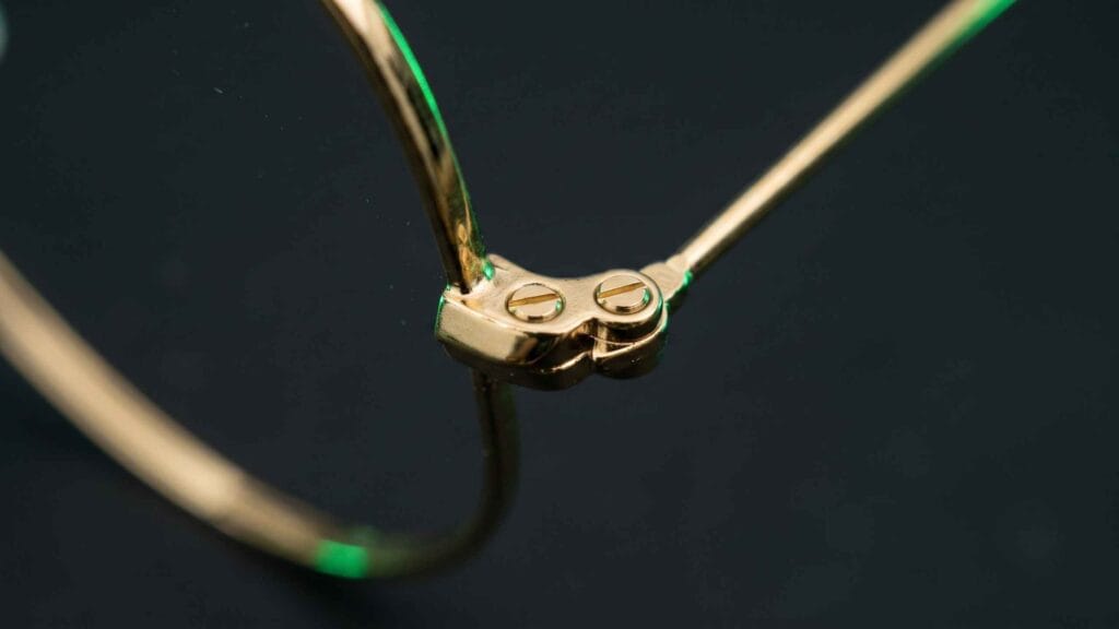 Extreme macro of the tiny rim closure screw at the top corner of a metal aviator sunglasses frame
