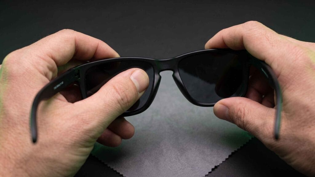 Thumb pushing a lens out of a flexible sport sunglasses frame from behind