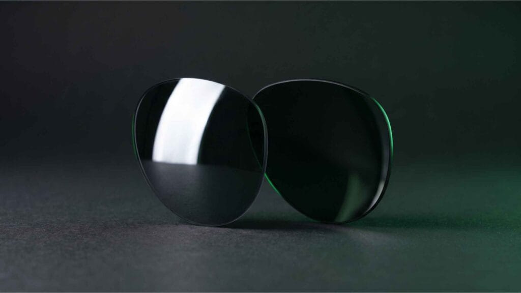 Two sunglass lenses side by side reflecting light differently on a dark surface